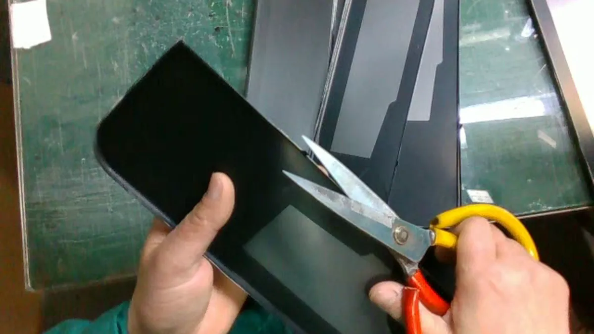 Head-mounted view of hands trimming protective film from a panel with scissors