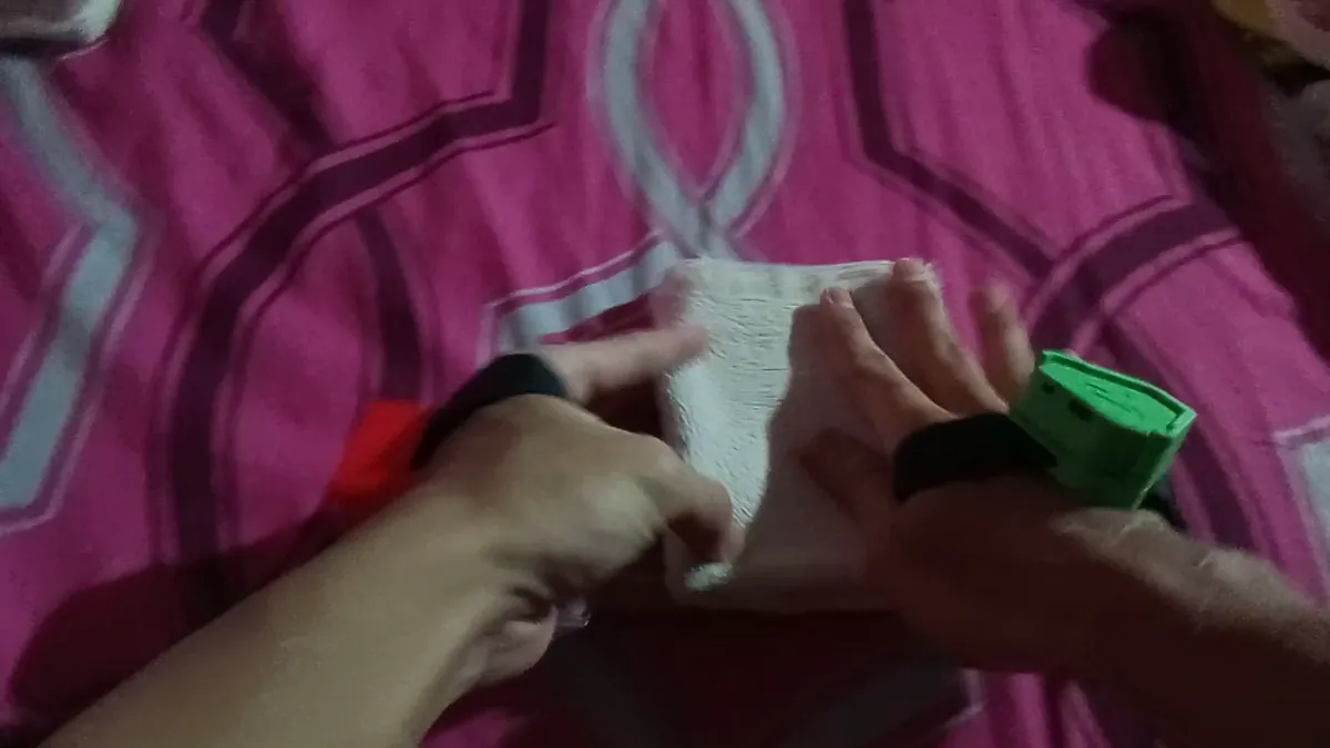 Head-mounted view of hands wearing IMU straps folding a towel on a bed