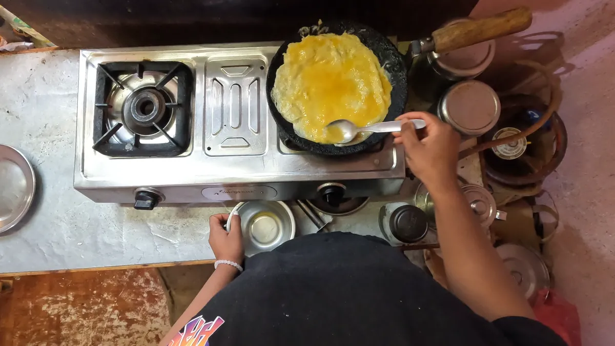 Head-mounted view looking down at hands cooking an omelette on a gas stove