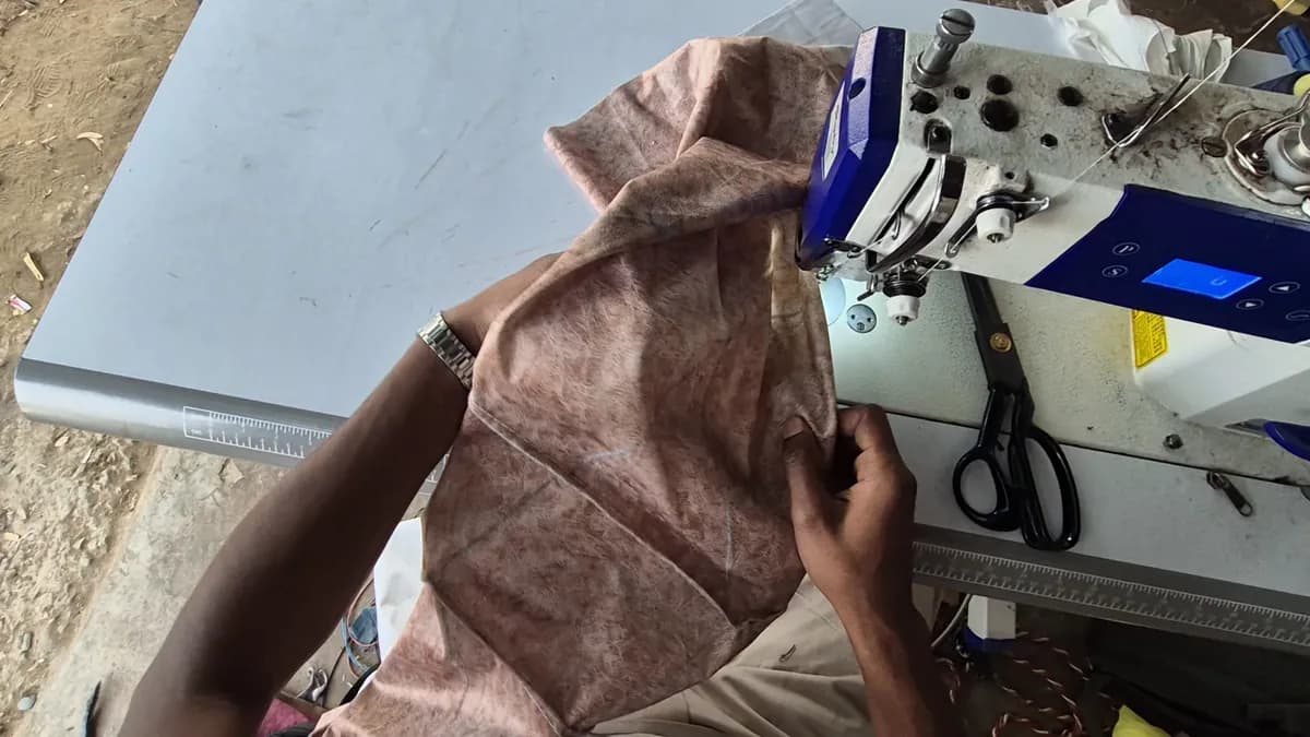 Head-mounted view of hands guiding fabric through an industrial sewing machine